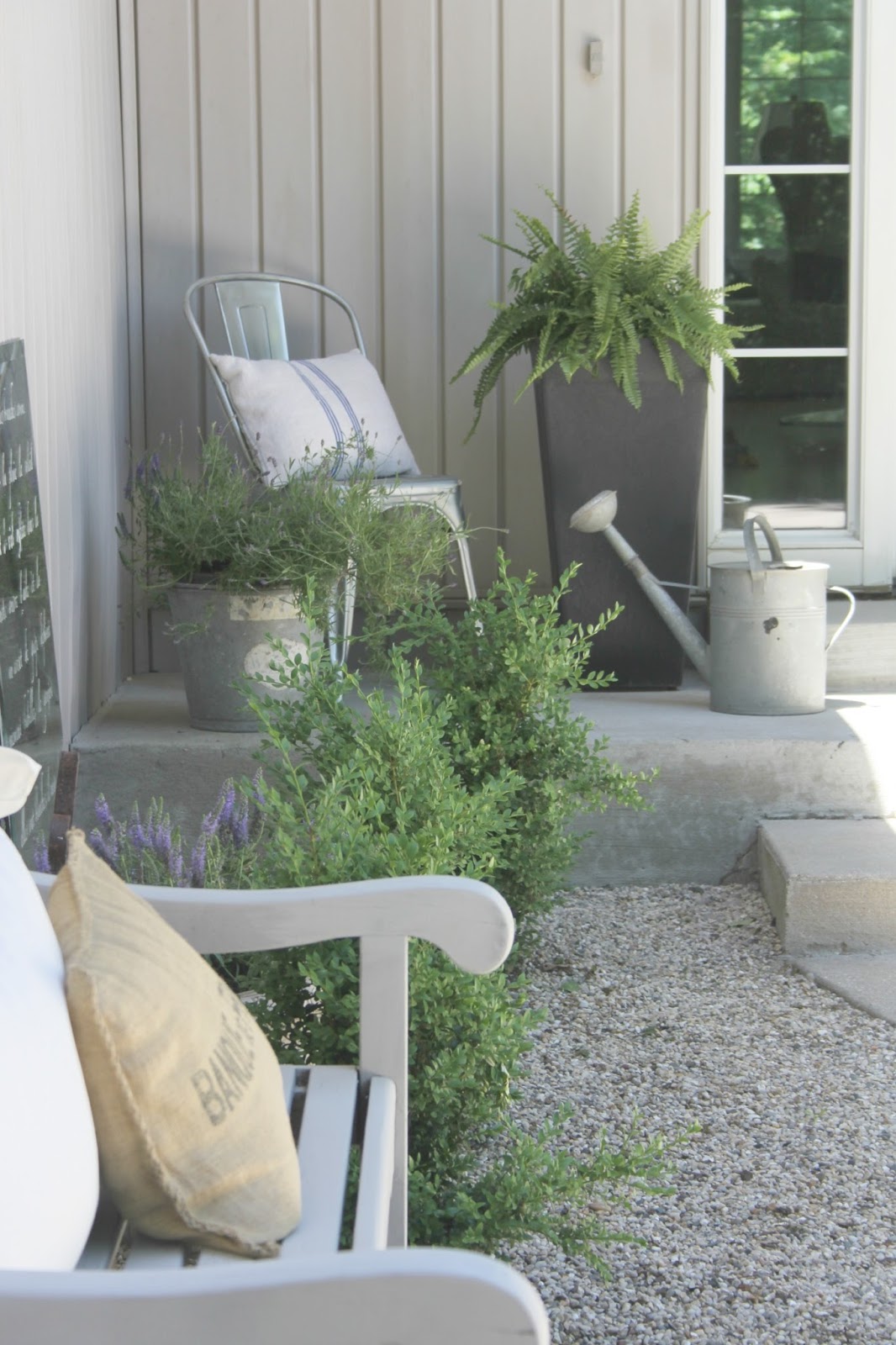 French Country decor inspiration in a French courtyard with pea gravel, boxwood, bench, and vintage decor. #hellolovelystudio #frenchfarmhouse #frenchfarmhouse #outdoordecor #courtyard #peagravel #boxwood