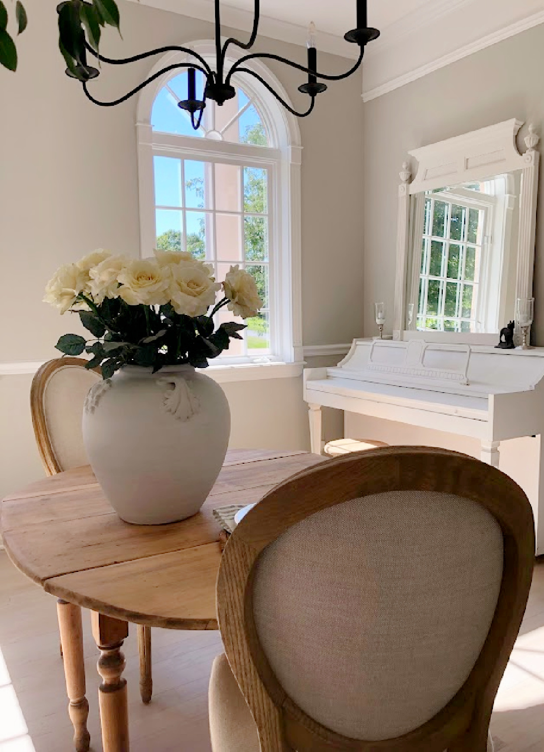 Hello Lovely's modern French dining room with piano and pot with white roses. Wall color is SW Repose Gray.