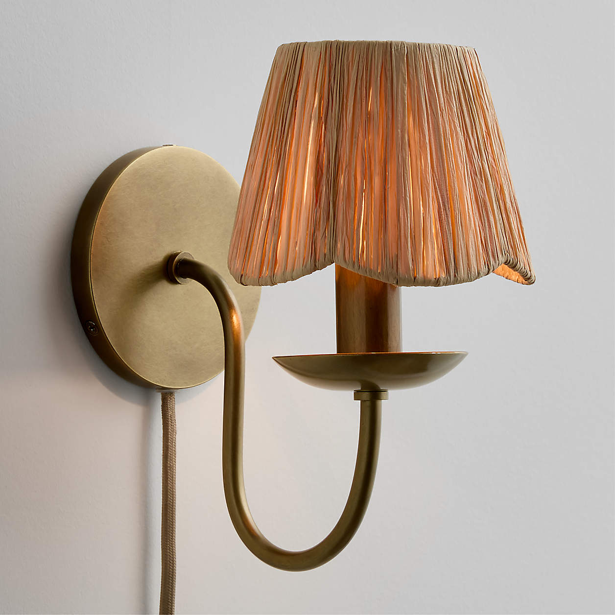 Greta plug-in sconce from Crate & Barrel has a scalloped raffia shade. #wallsconce #scallopeddecor #lightfixtures #ad