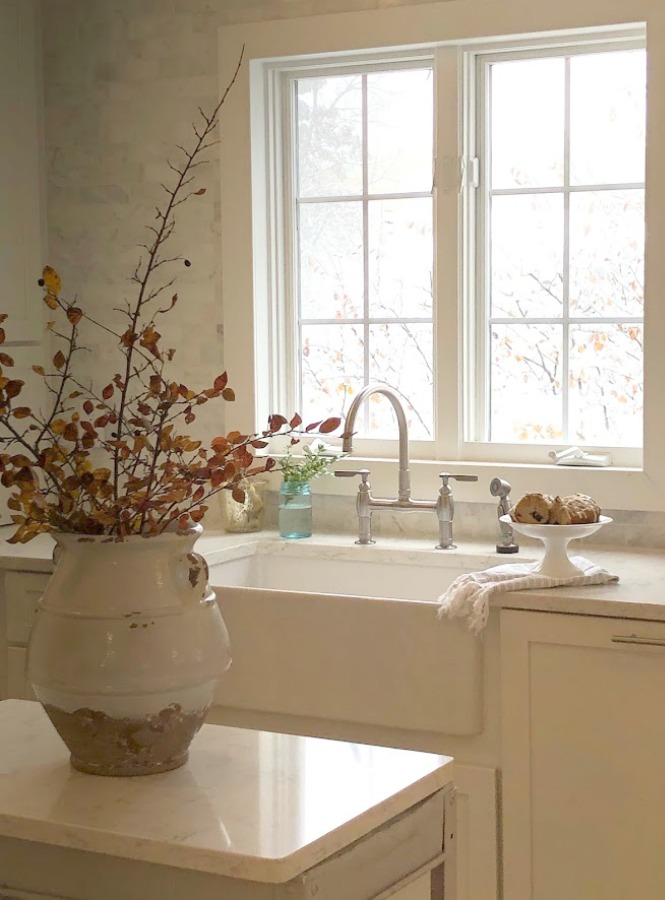 Hello Lovely's serene white kitchen with farm sink, rustic steel work cart, and Minuet quartz (VIATERA LX Hausys).