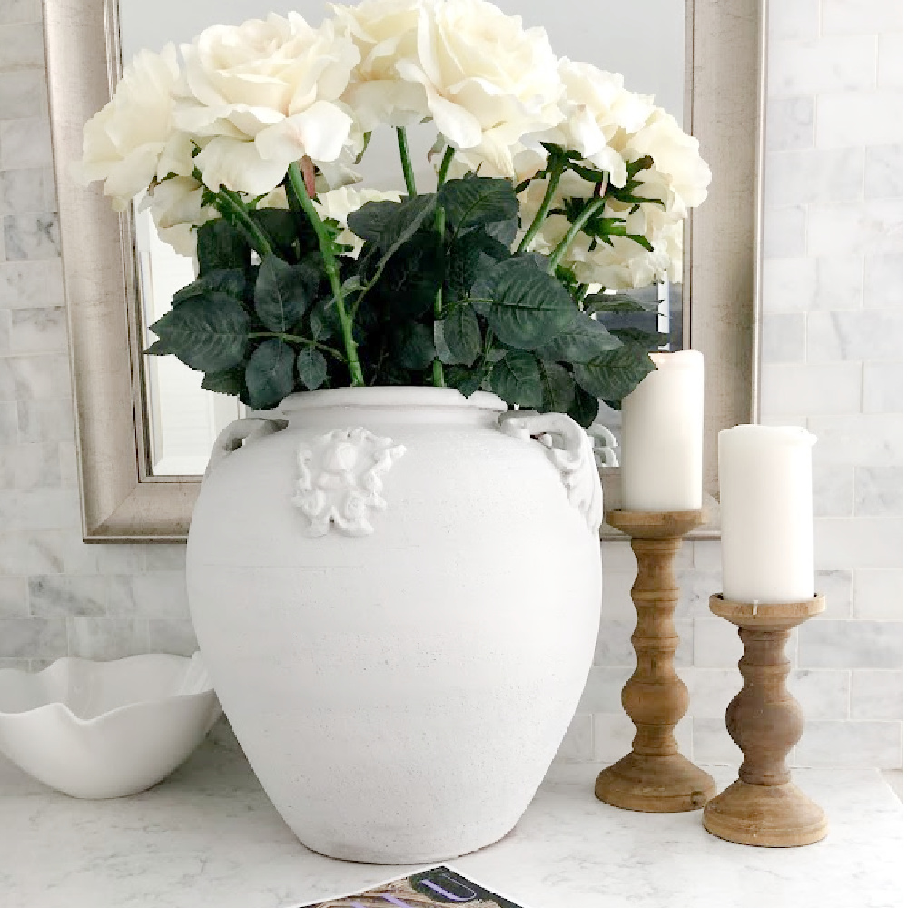 Hello Lovely's white marble kitchen with large urn of white roses.